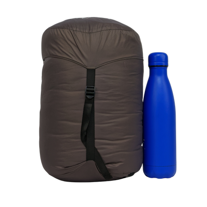 Sac de couchage Lodenn, marque Freetime, duvet température confort -1°C pour moins de 1kg ! vue dans son sac de transport à côté d'une gourde de 500 ml (photo détourée)