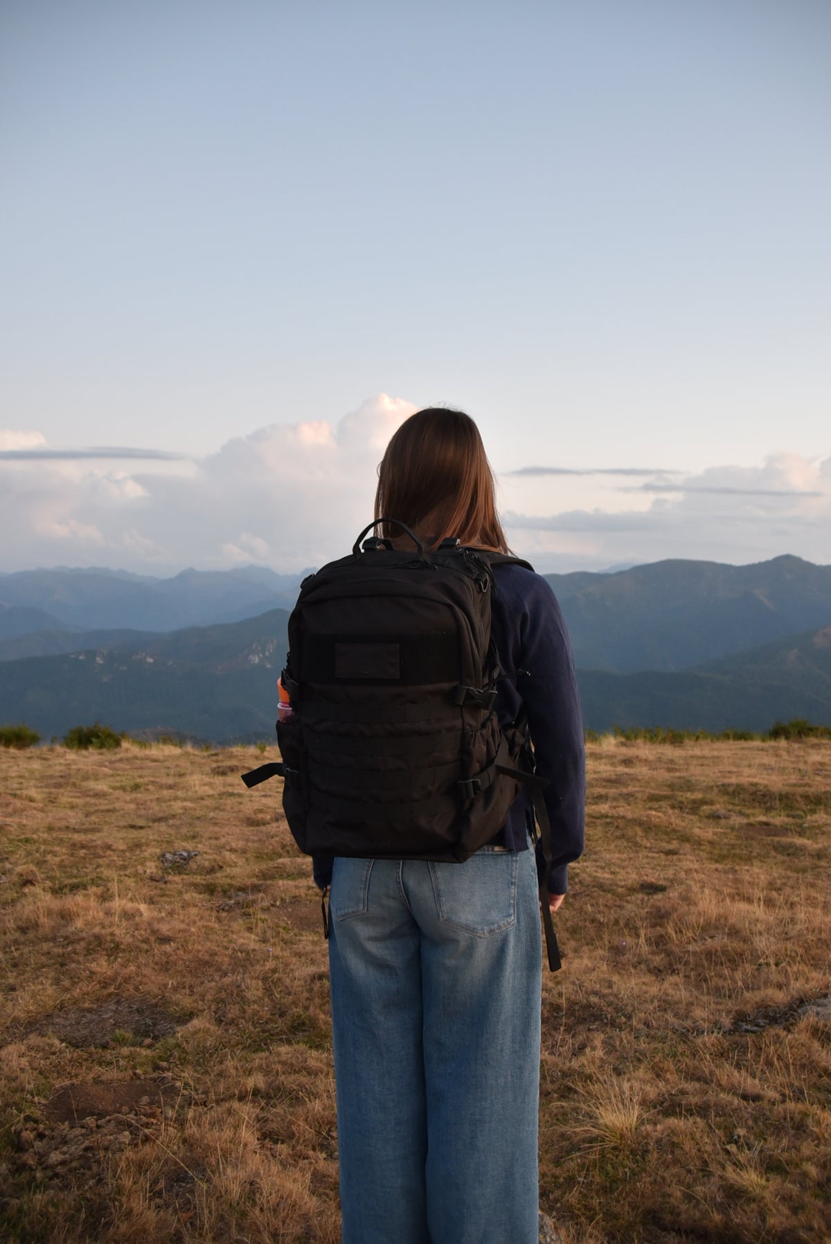 Sac d'évacuation Mangouste 32, marque Freetime, capacité 32 litres - sac noir avec système MOLLE et compartiment ordinateur, vu porté par une jeune femme dans le Cantal - crédit @cestmeline