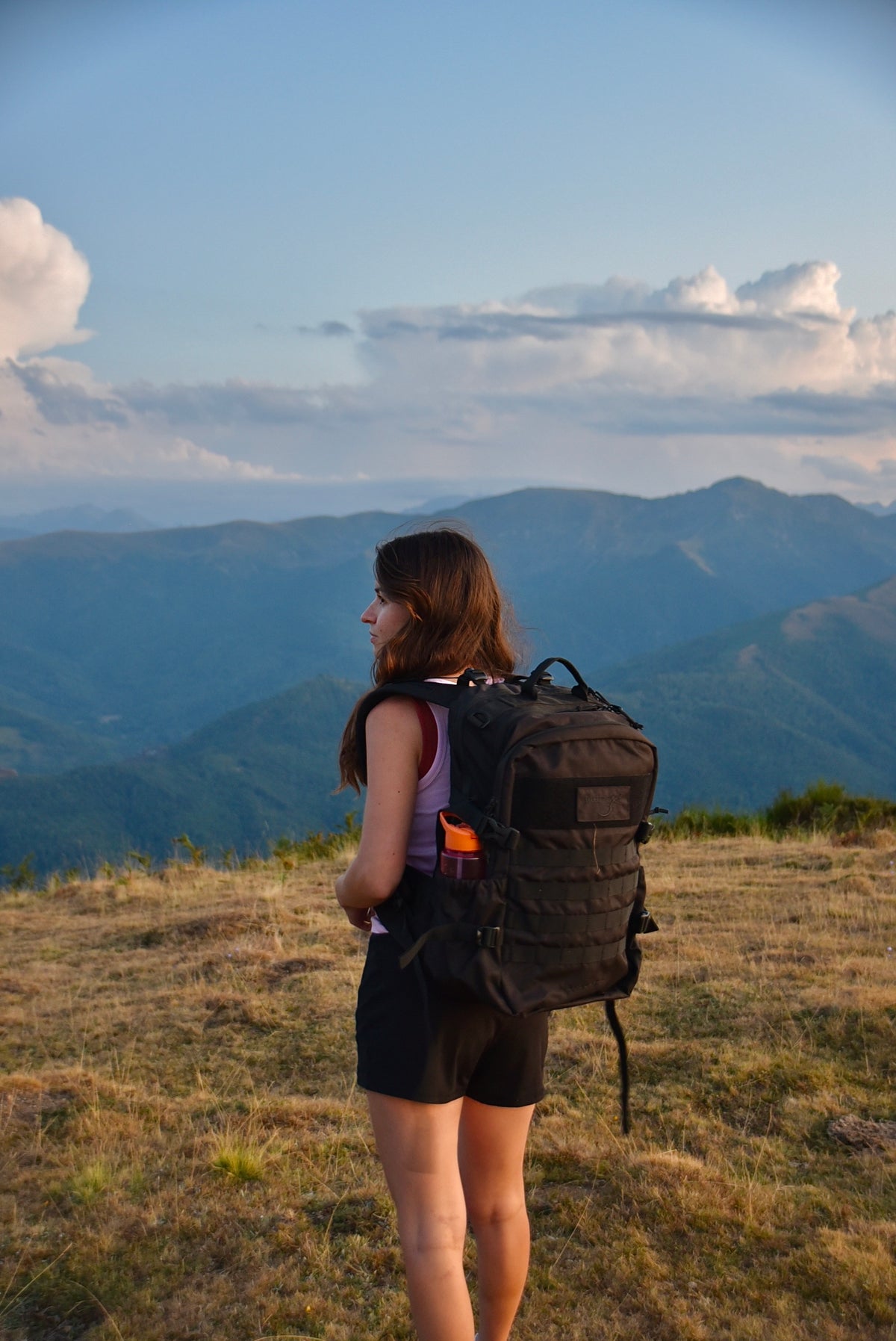 Sac d'évacuation Mangouste 32, marque Freetime, capacité 32 litres - sac noir avec système MOLLE et compartiment ordinateur, vu porté par une jeune femme à la montagne - crédit @cestmeline